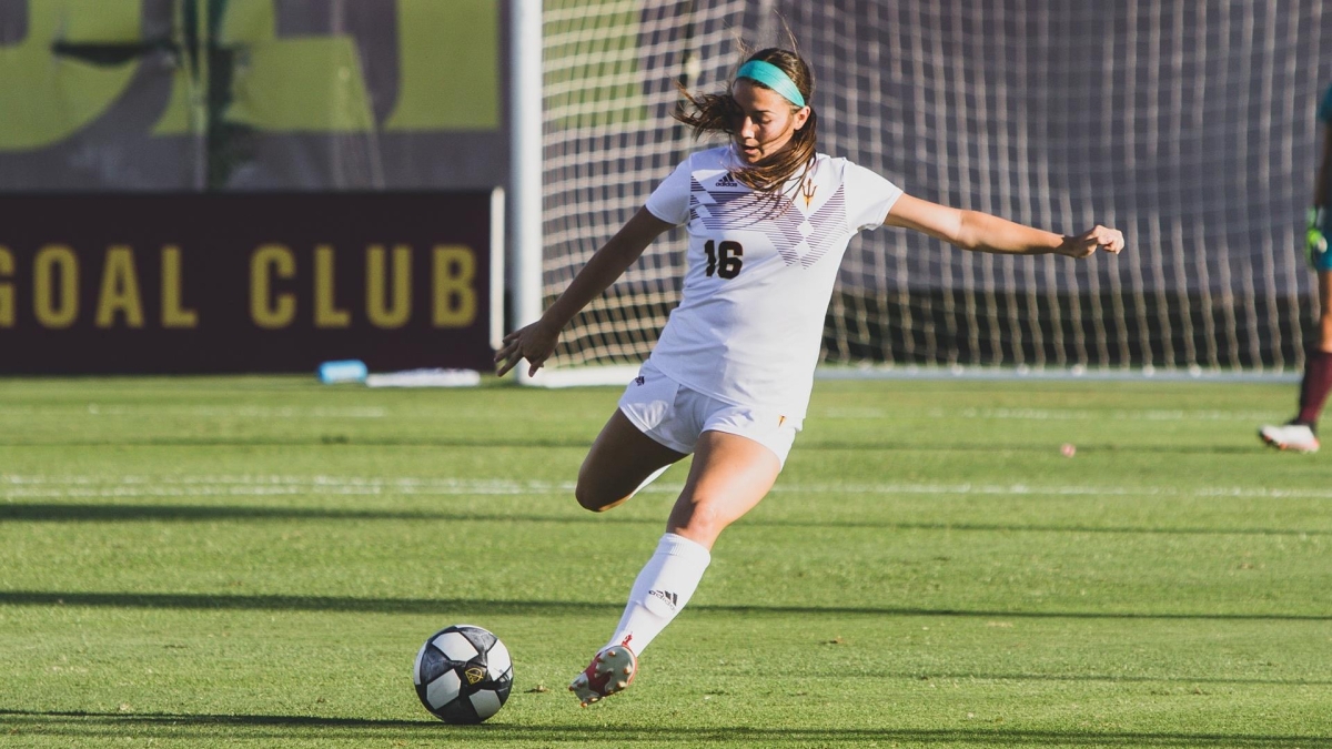 ASU student Nicole Soto winding up to kick a soccer ball on a field.