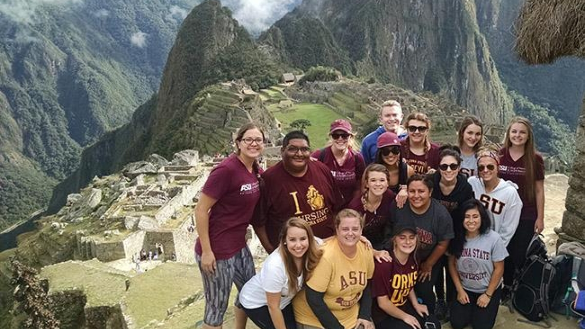 A group of ASU students pose at Machu Picchu in Peru. The students are grouped together with the famous mountain range in the background
