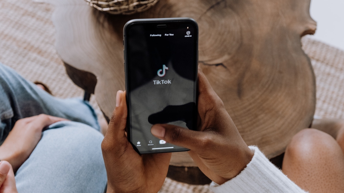 Closeup of a Black woman's hands holding a phone and opening the TikTok platform.