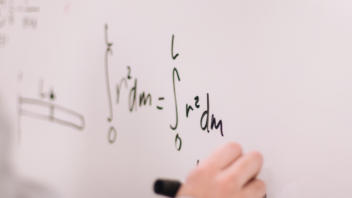 Person writing equations on white board