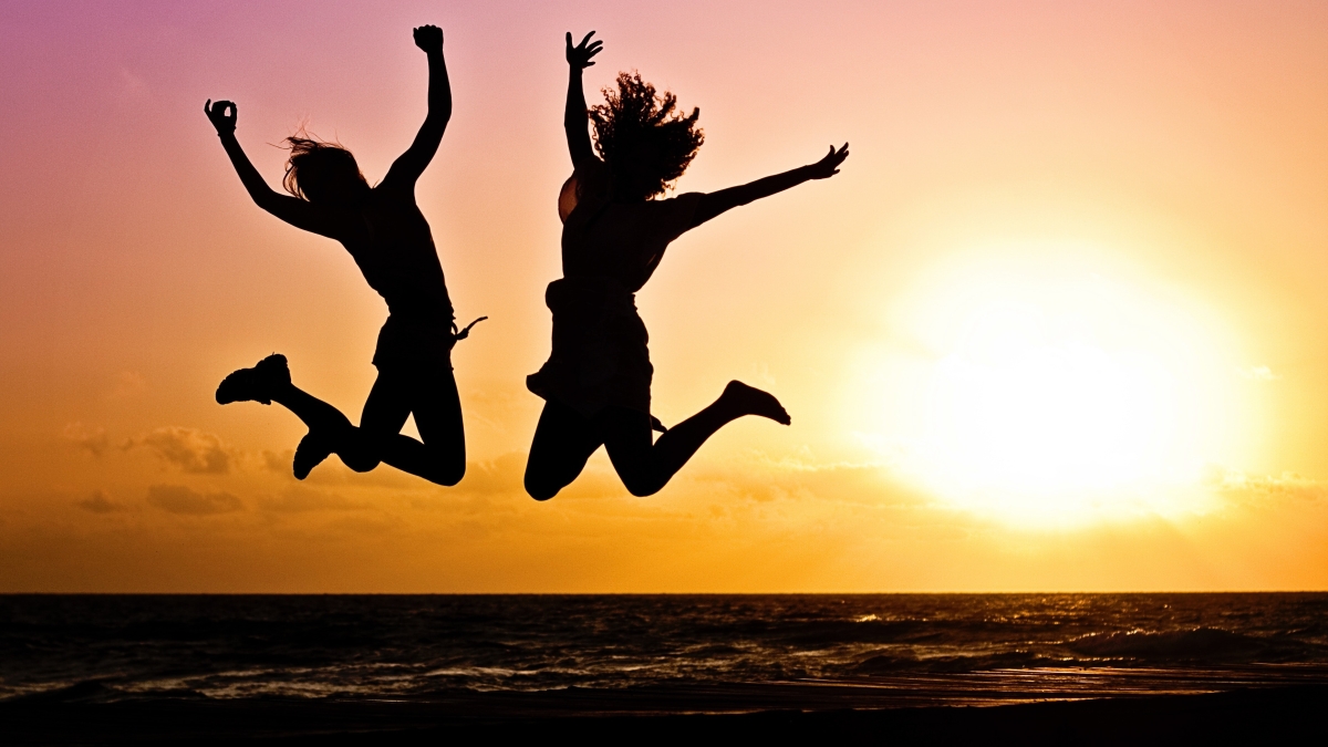 Two people jump for joy as the sun sets behind them.