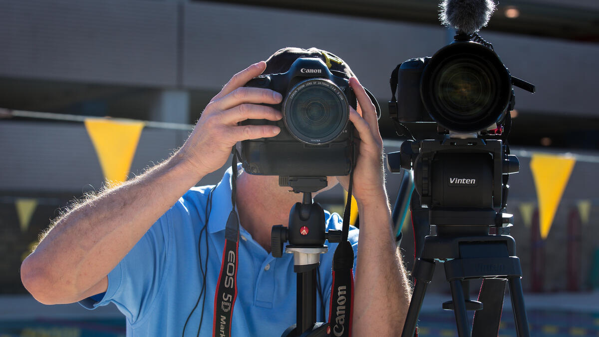 A man adjusts two video cameras
