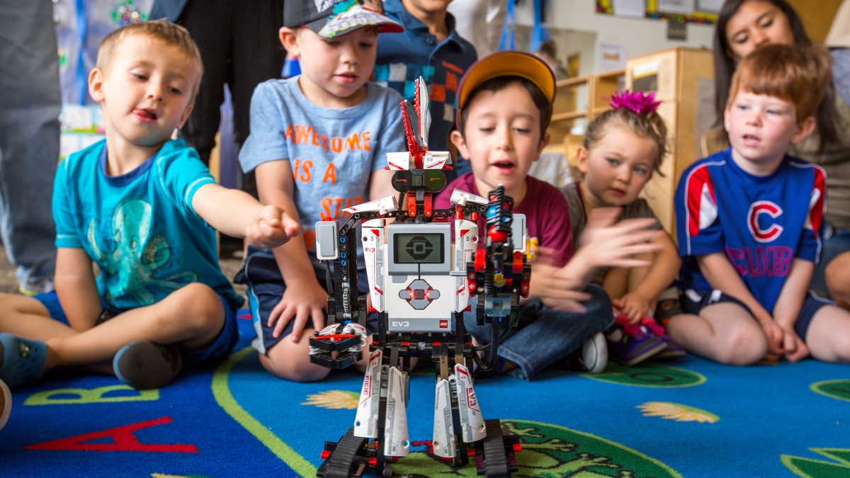preschoolers sit on ground and watch a robot move