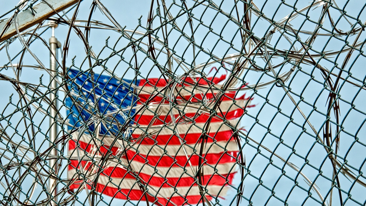 Picture of American flag behind barbed wire.