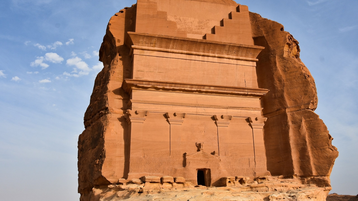 Large, sandstone tomb with carved facade at the Hegra heritage site in Saudi Arabia.