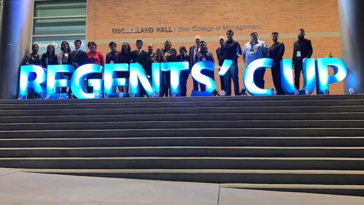 Students stand behind a sign spelling out Regents Cup