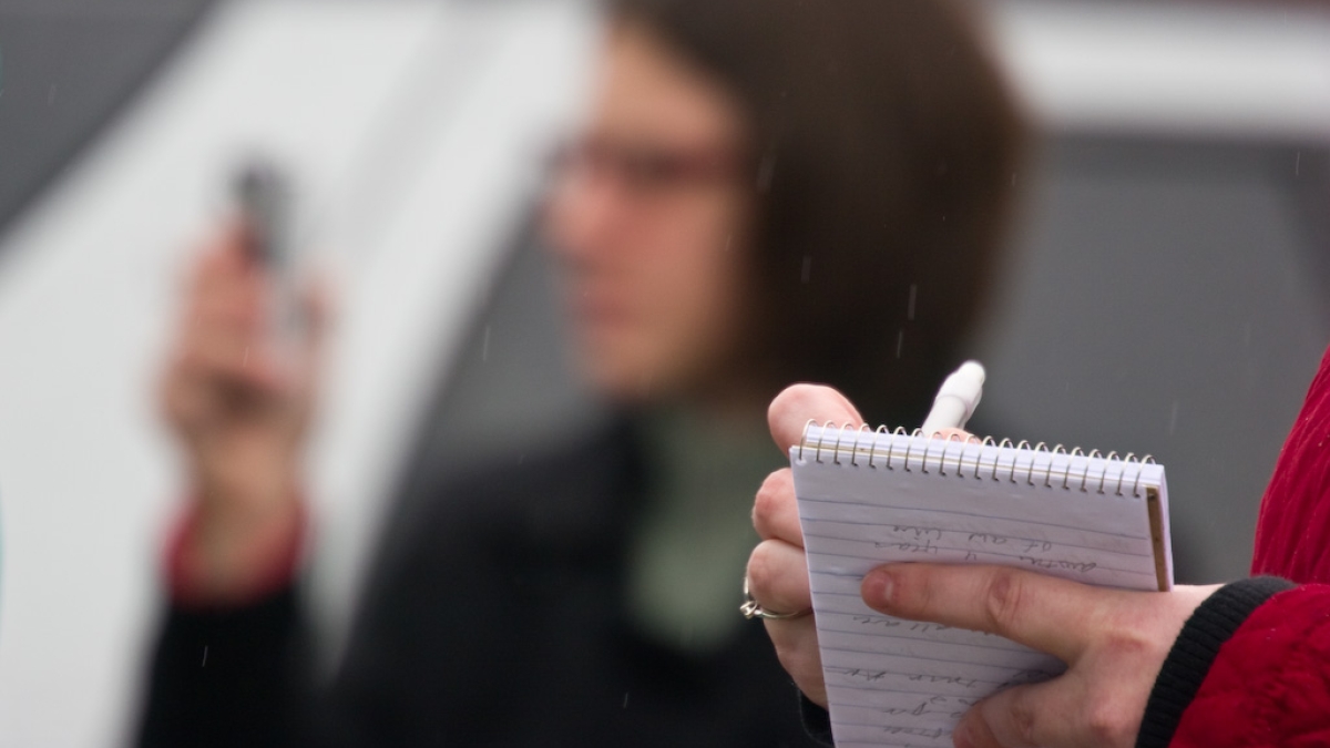 Woman in foreground holding a reporter's notebook