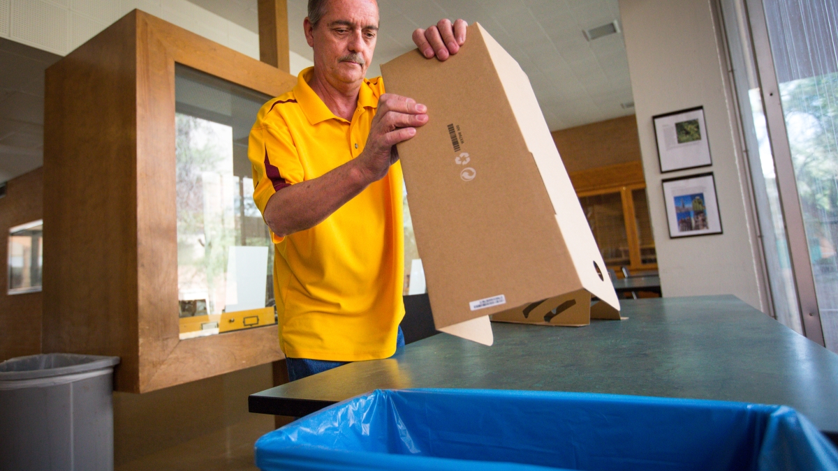 man putting cardboard into recycling bin