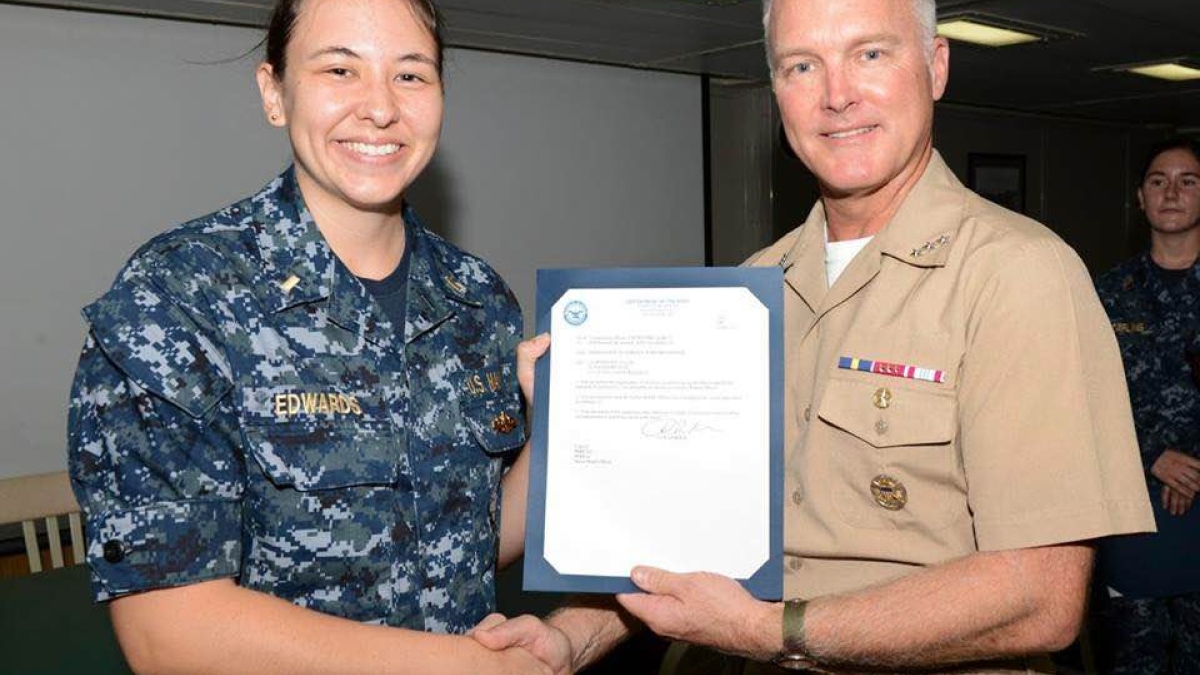 Vice Admiral Thomas Rowden awards Ensign Rachelle Edwards her surface warfare officer pin.