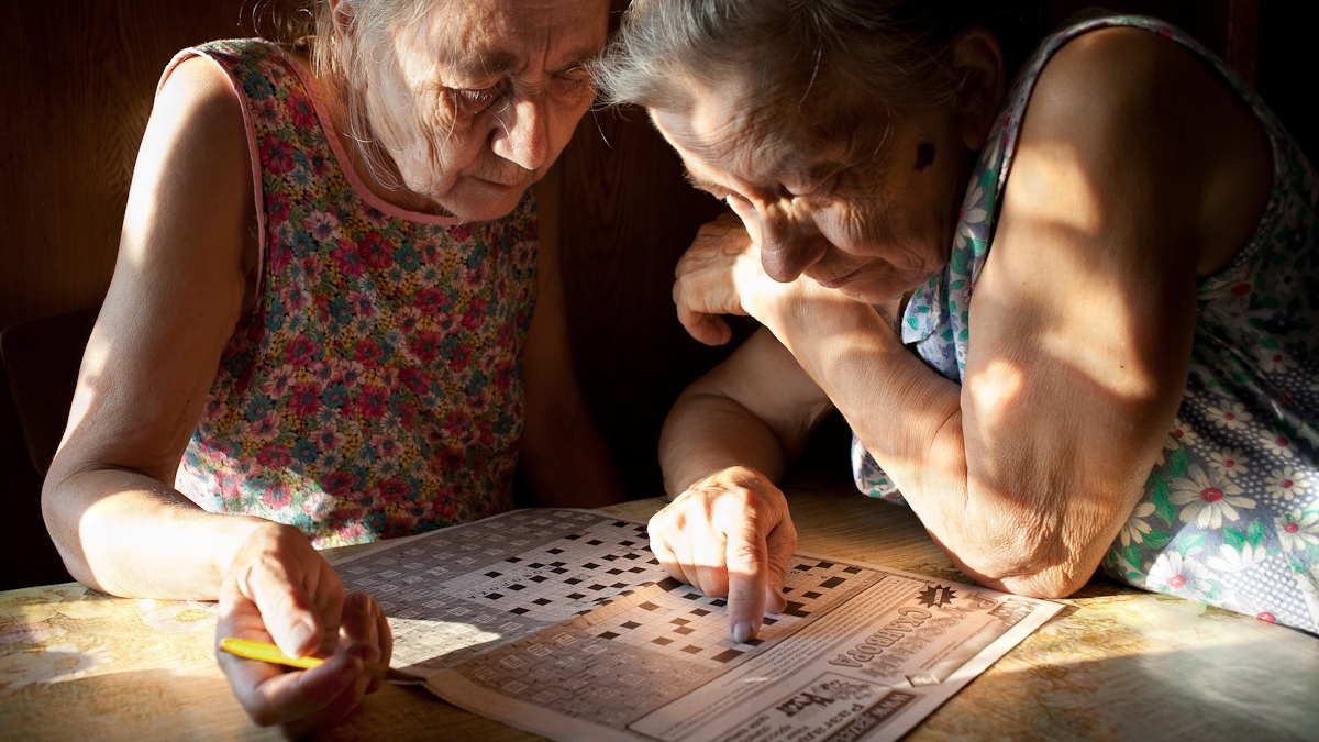 Two older women playing a crossword puzzle