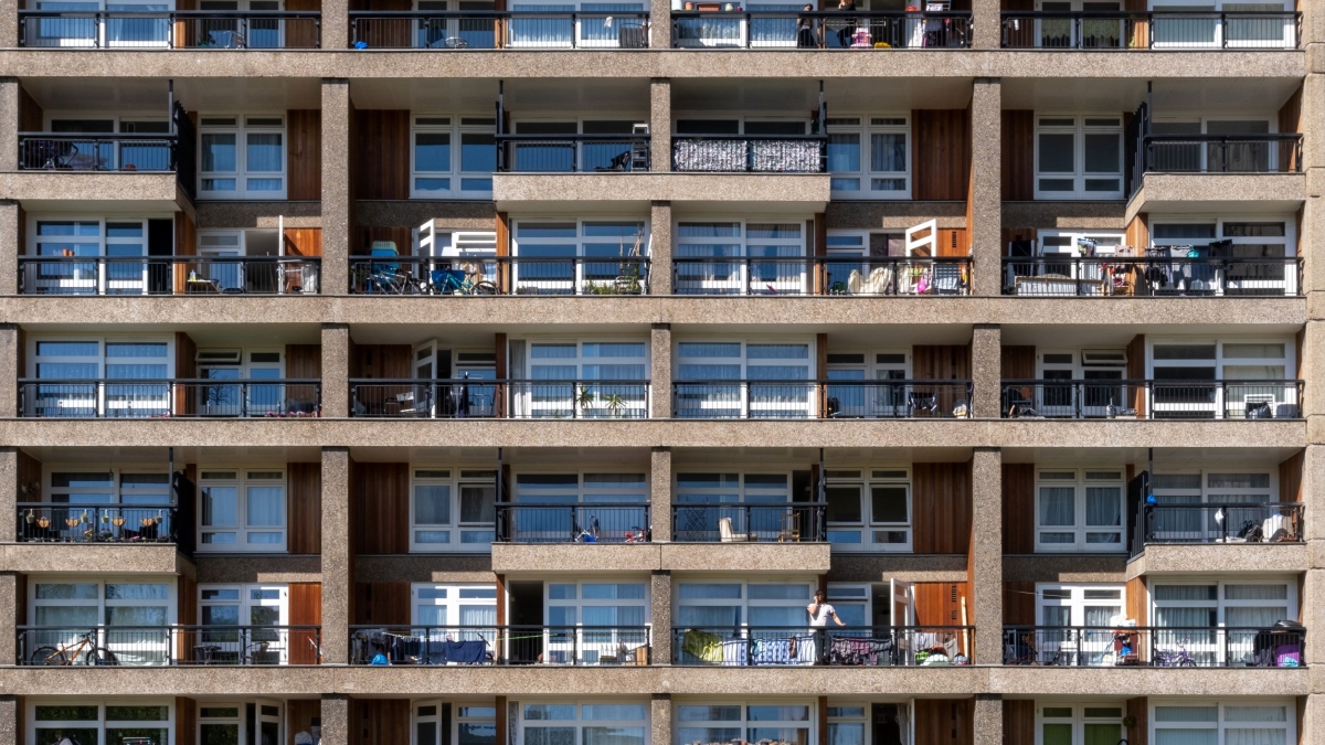 Exterior of an apartment building showing several balconies with a variety of furniture and some people.