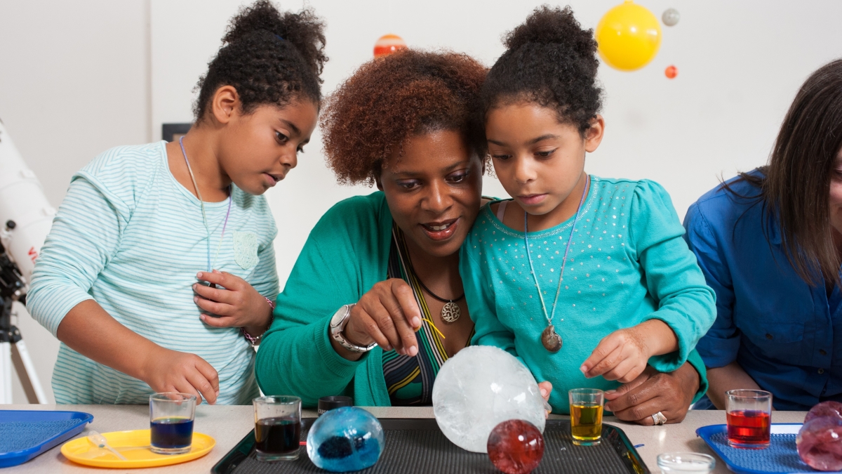 woman and children working on science experiment 