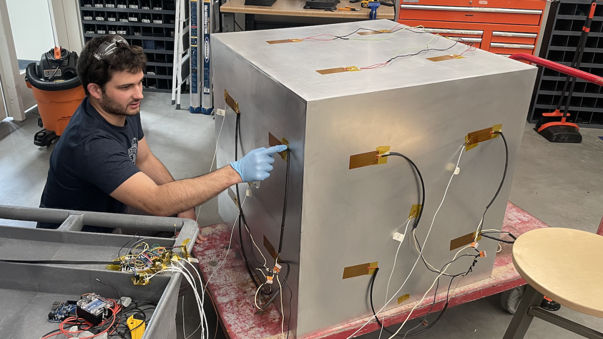 ASU student worker Matthew Adkins working on a cubesat in a lab.