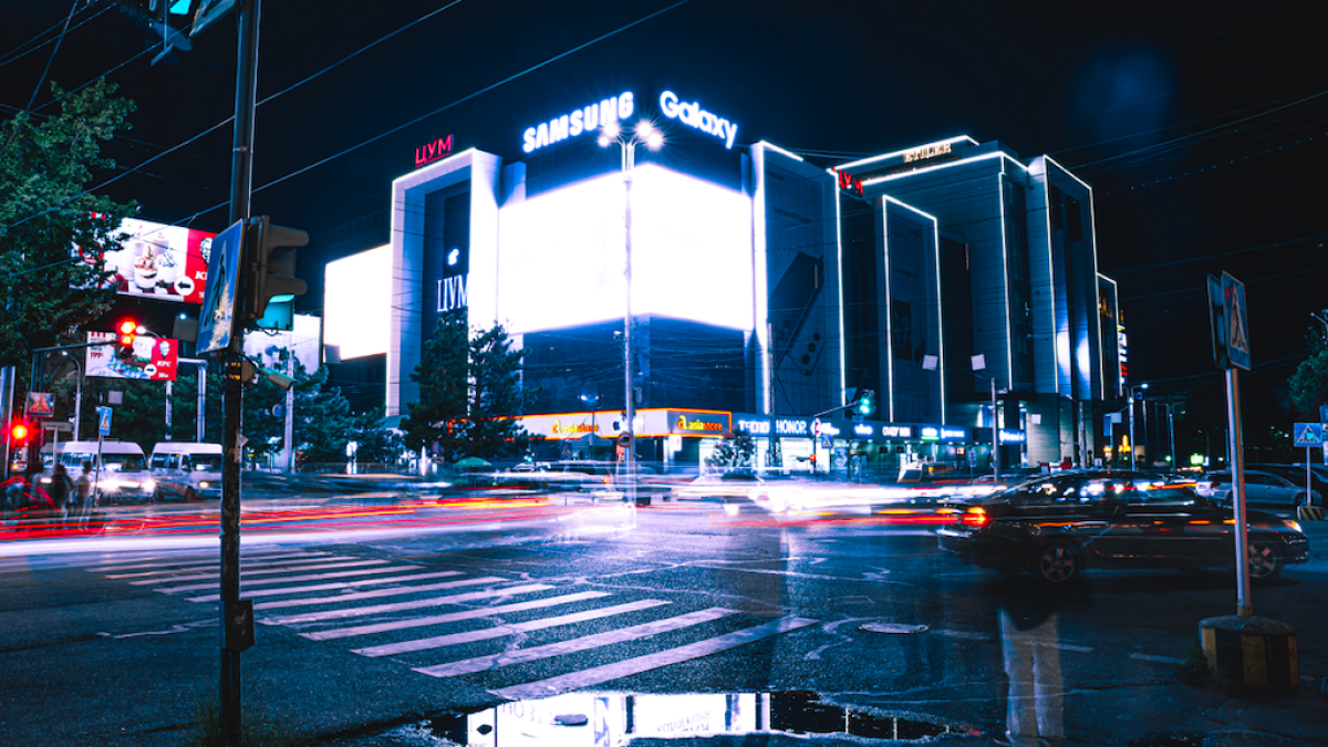 Photo of an intersection in Kyrgyzstan with traffic and brighlty lit buildings.