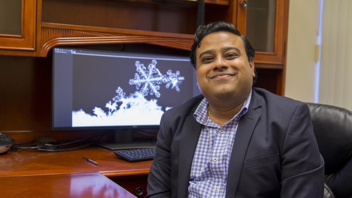 A photo of Kumar Ankit in front of a computer monitor displaying a snowflake.