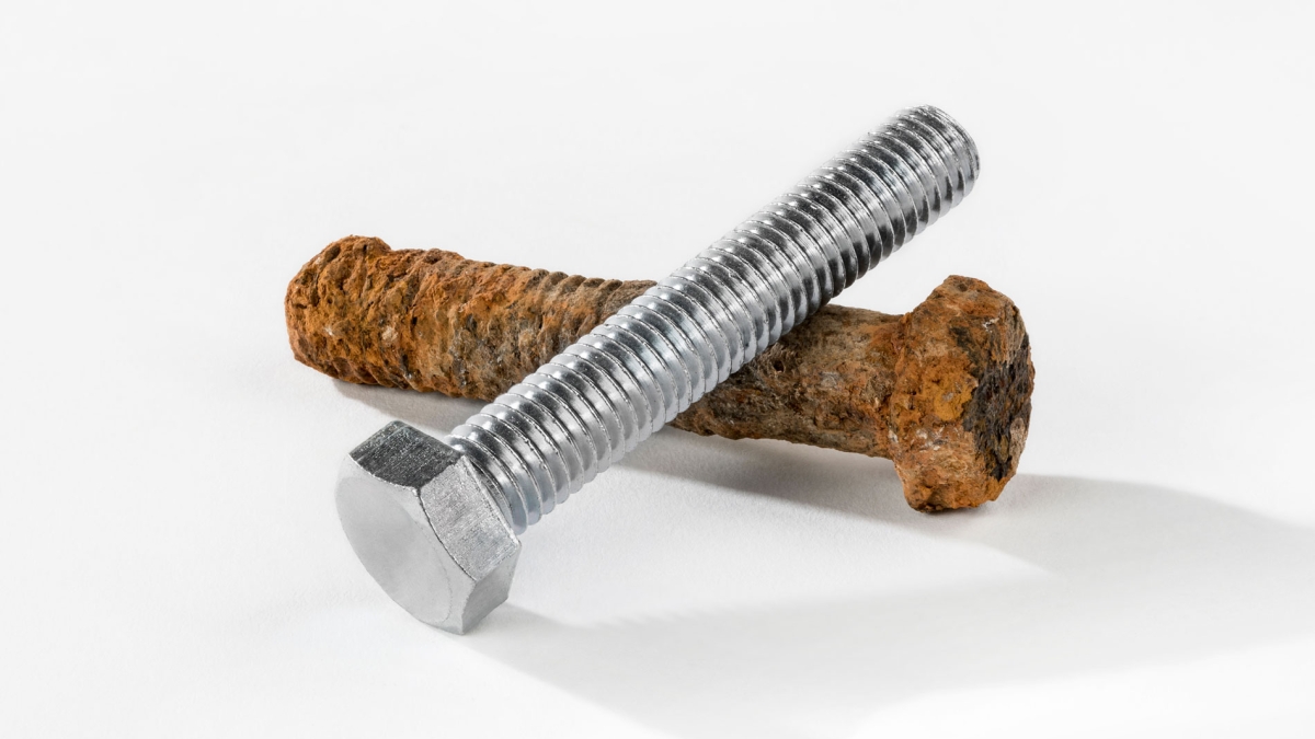 A rusty screw and a new screw show the destruction of corrosion on metal and metal alloys.