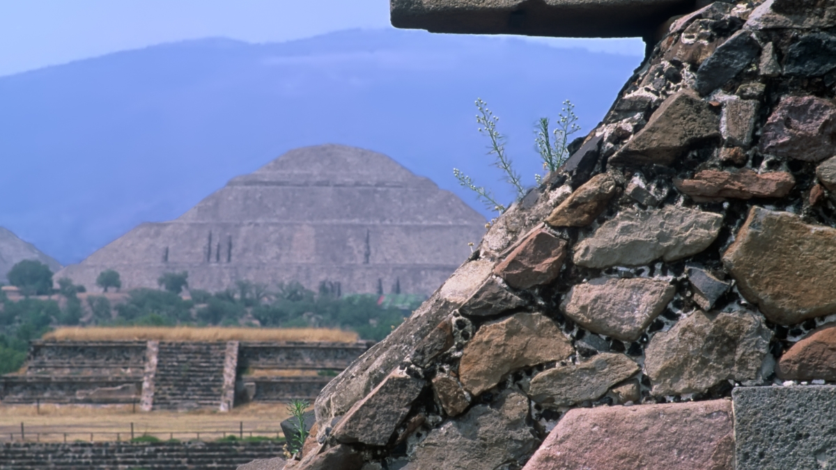 Carved jaguar head on the Temple of the Feathered Serpent, pyramid in background
