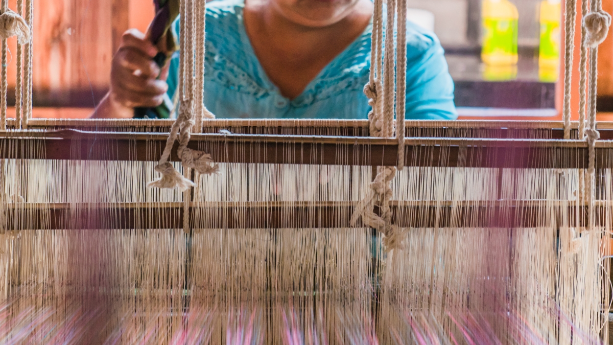 A woman weaves at a traditional loom