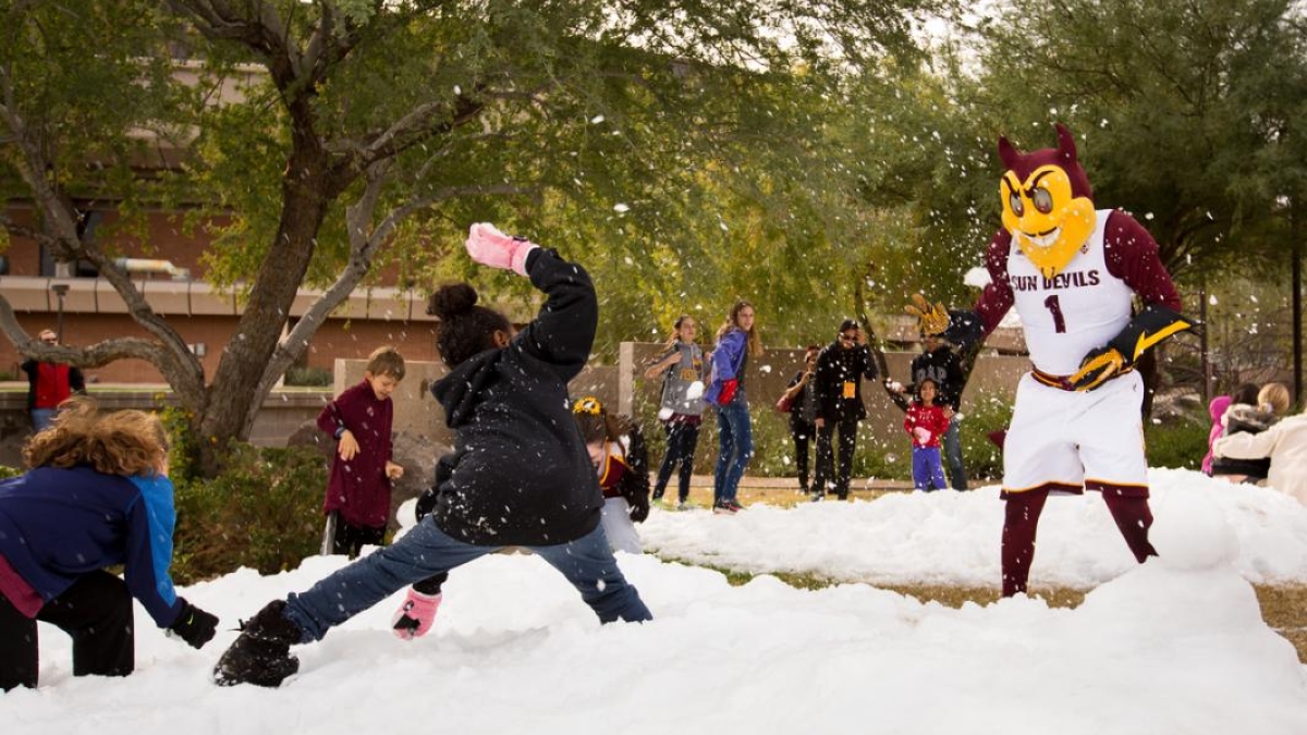 Children pelt a mascot with snowballs.