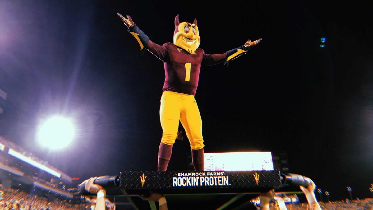 ASU mascot Sparky stands on a platform held by other students at a football game