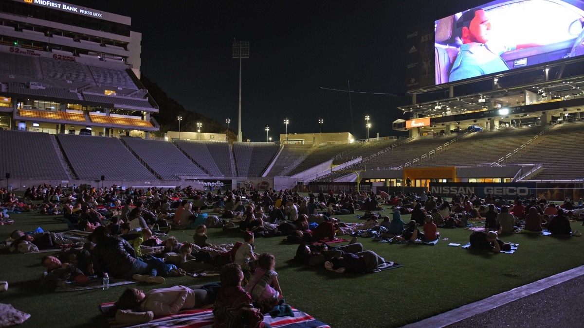 Family lie on blankets on the ASU football field to watch a Spider-Man movie