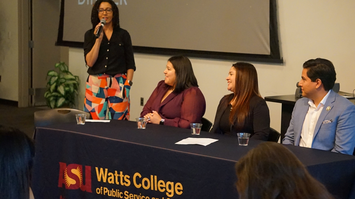 Panelists sit or stand at a Watts College table.
