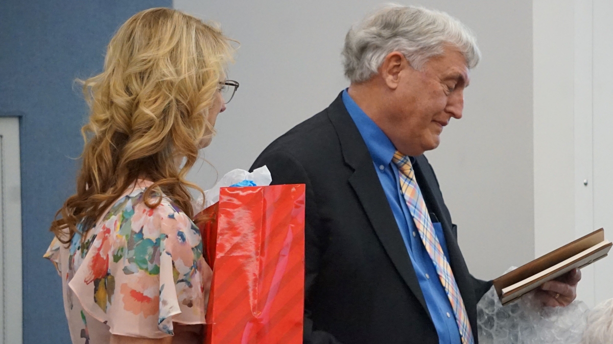 Richard Knopf reacts to receiving a plaque honoring him as he retires