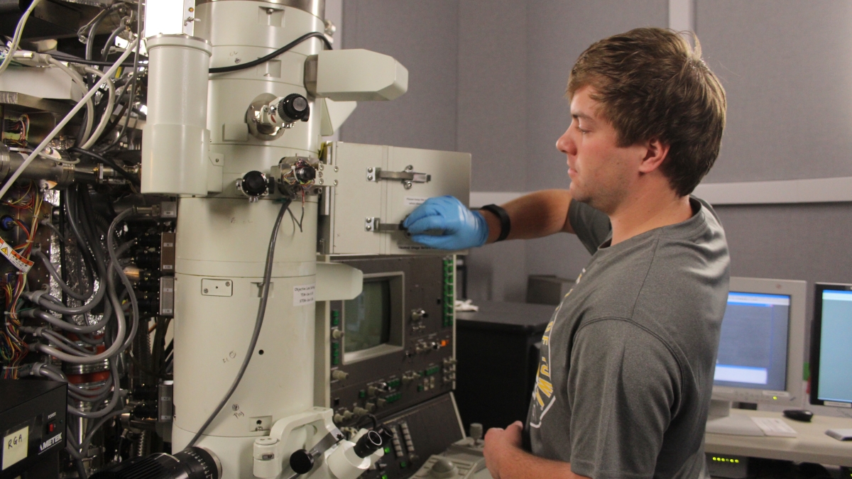 A student works on a large microscope.