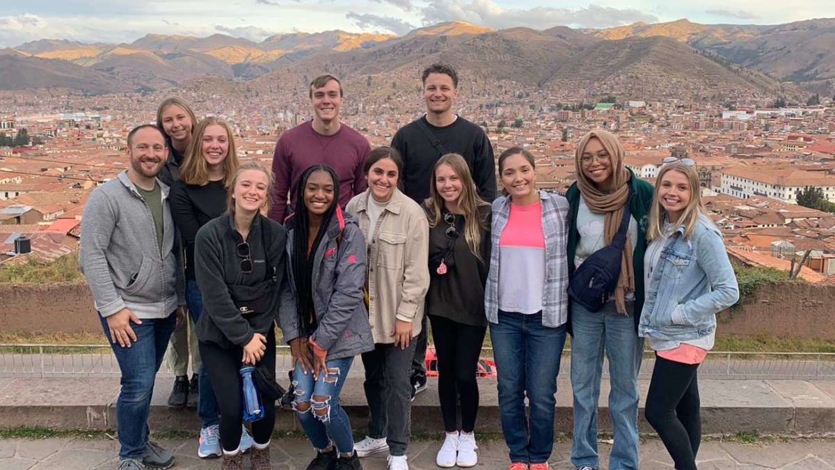 ASU students pose for a photo during their study abroad trip to Peru. In the background mountains and a city are visible.