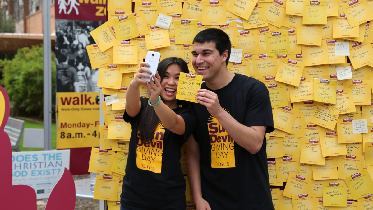 Students take a selfie in front of a board full of Sun Devil Giving Day notes.