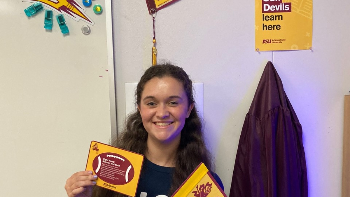 ASU alum and current teacher Jenna Brooks smiles and holds up some ASU-themed swag she received as part of a Sun Devil teacher pack.