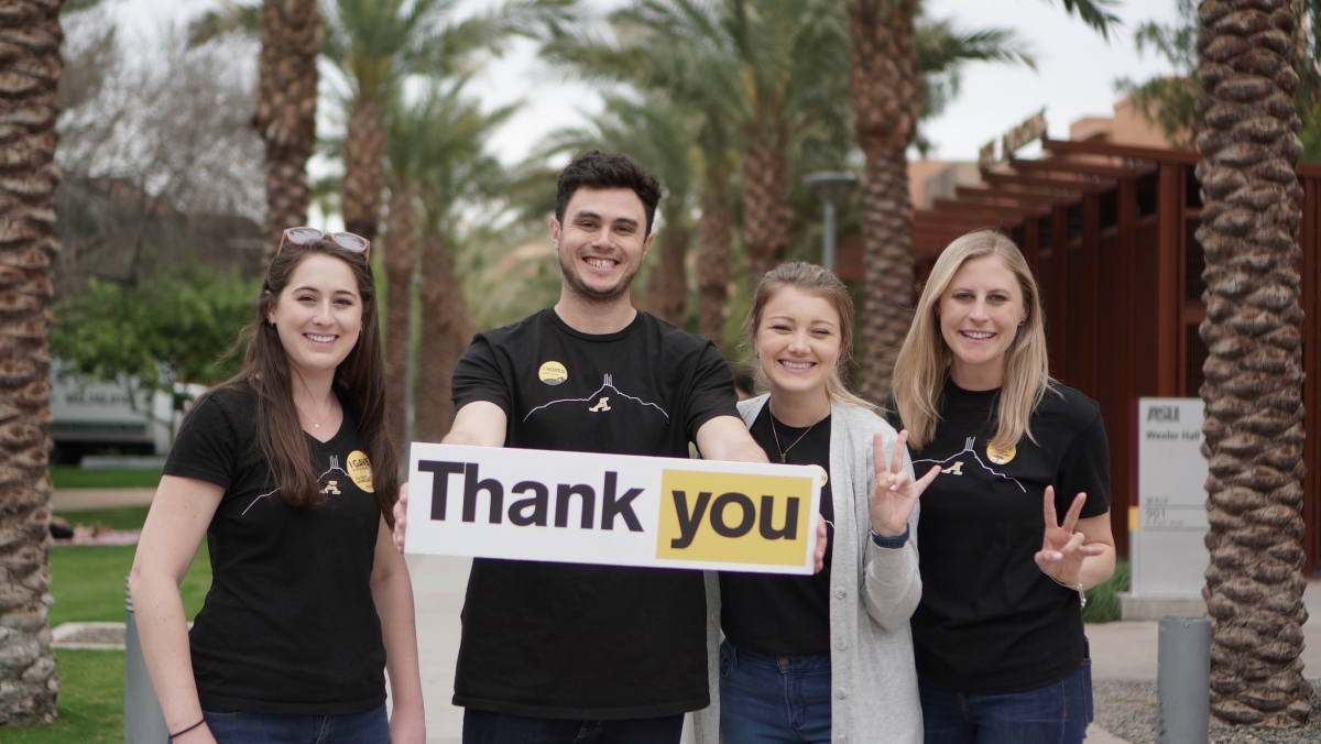 Four people hold a thank you sign to show support of Sun Devil Giving Day