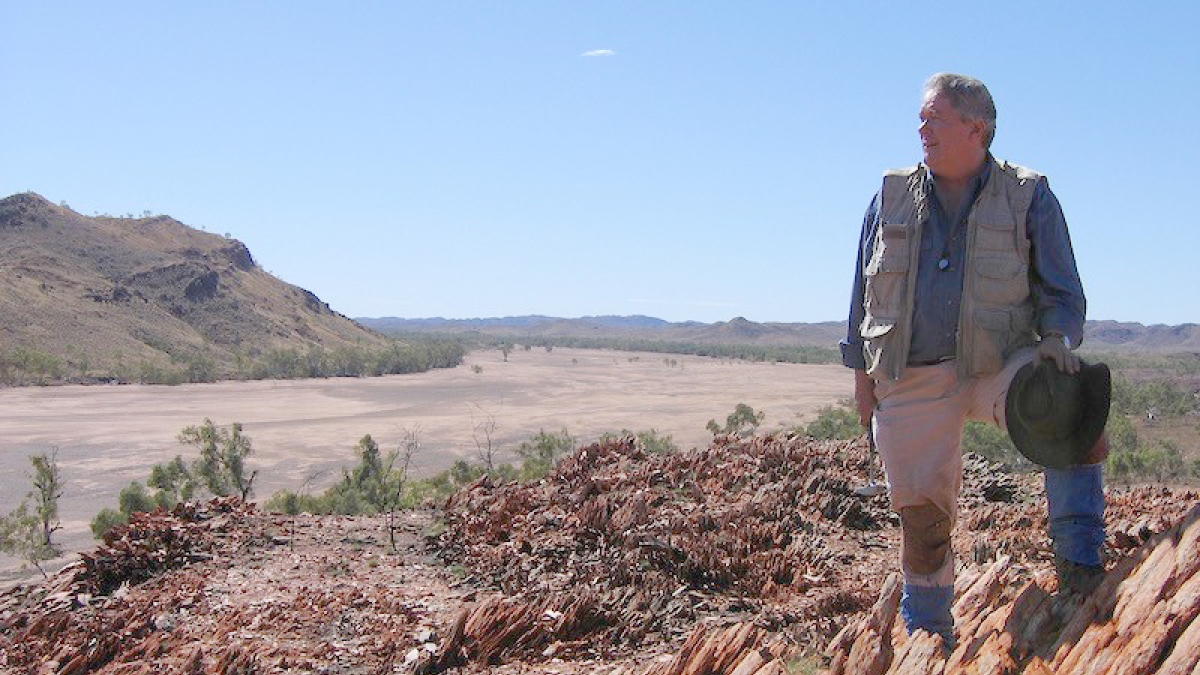 Man standing on rocky terrain in an outdoor setting.