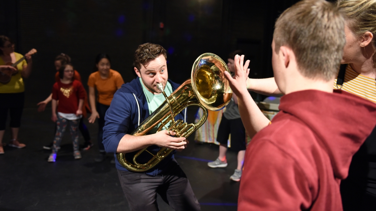 children watch a man playing the tuba