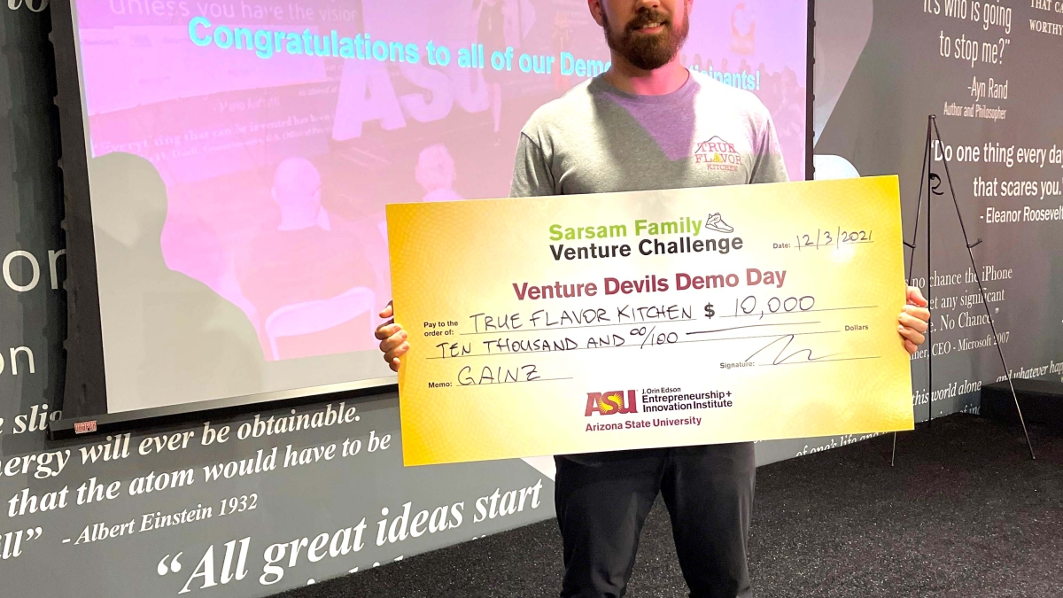 Tyler Perez holds oversized check showing his $10,000 win from Venture Devils Demo Day.
