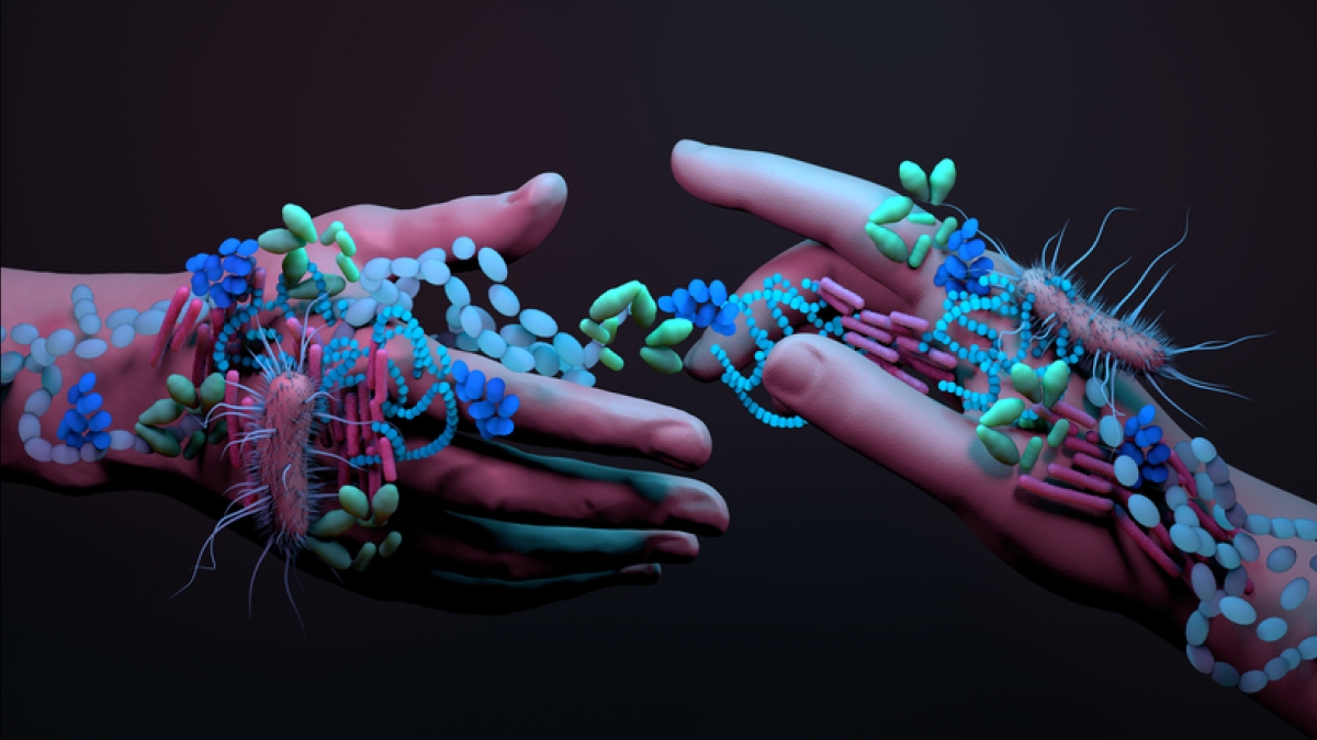 Two hands covered in illustrations of microbes as they reach toward each other.