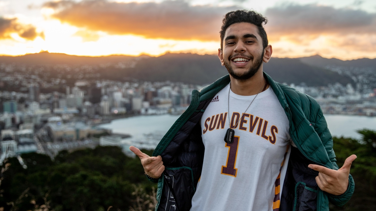 man wearing ASU Sun Devils jersey on a mountain with a city in the background