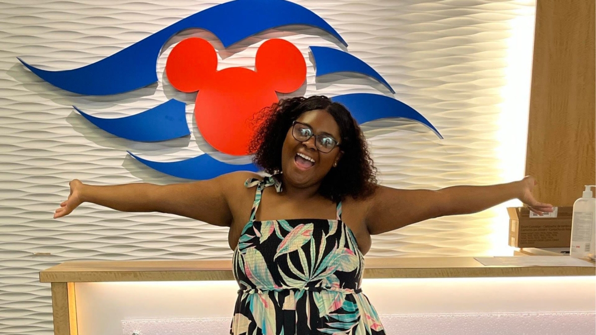 Smiling woman standing in front of a Disney Cruise Line logo.