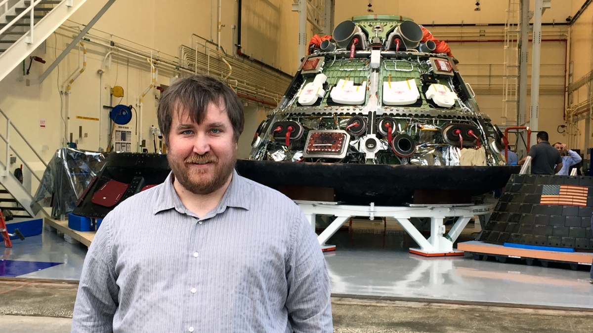 ASU alum Zachary Pirtle stands in front of an Orion spacecraft at NASA