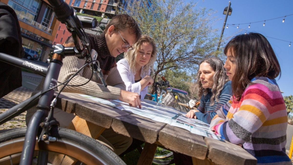 A group of four ASU researchers sitting at a table looking at a map.