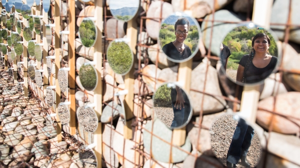 two people reflected in circular mirrors as part of a desert installation