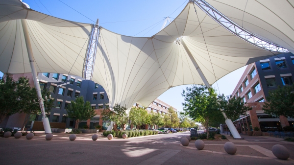 Shade structures that look like large white sails stand over an outdoor plaza