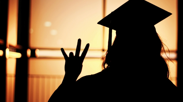 silhouette of student in a cap making a pitchfork with hand