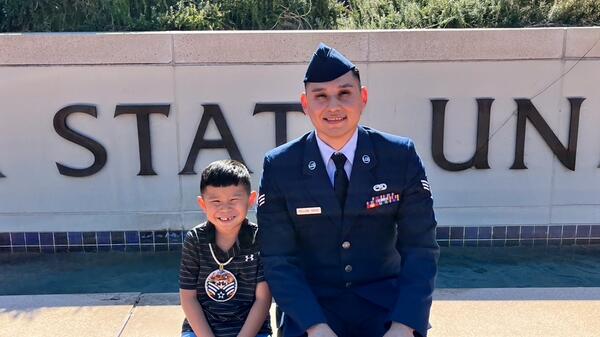 Man in a U.S. Air Force uniform seated next to a young child.