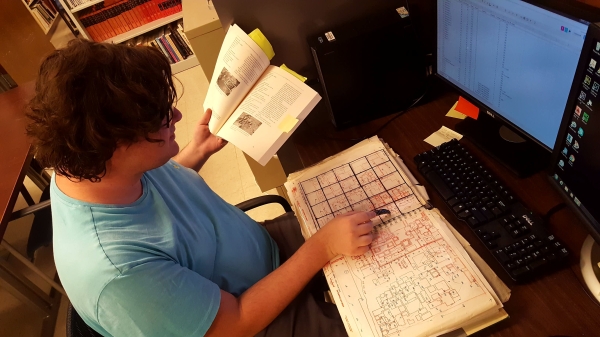 Intern, Noah Livingston, looking at the Teo Mapping Project and pointing with a piece of obsidian