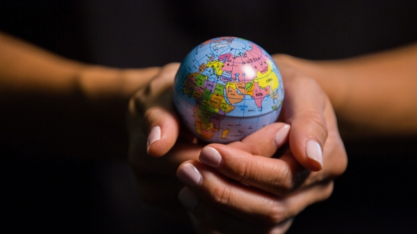Two hands hold a tiny globe of the Earth