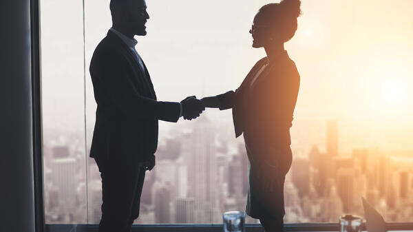 Two people shaking hands in front of window