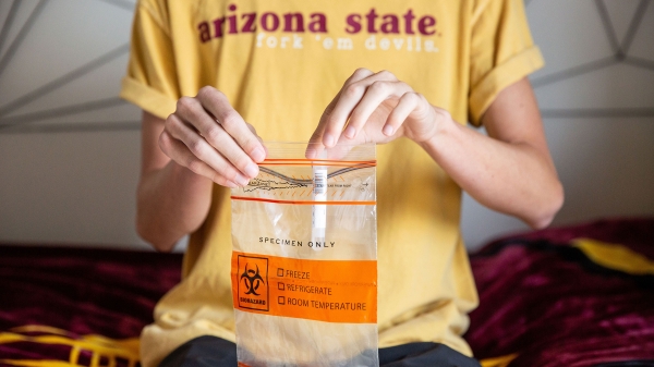 A student puts a test tube into a biohazard bag
