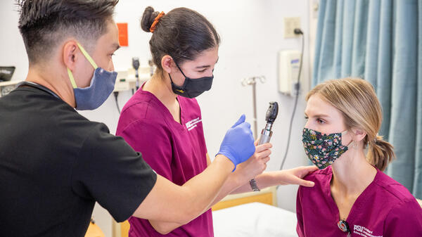 Nursing student practices looking into eyes of other nursing student