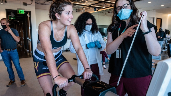 woman on stationary bike seeing health results on an ipad